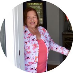 a woman standing in front of a door with her arms out and smiling at the camera