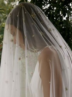 a woman wearing a wedding veil with gold stars on the top and bottom of her veil