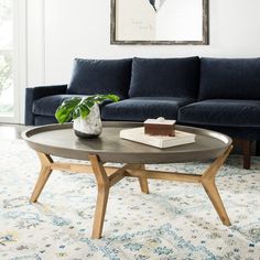 a living room with a blue couch, coffee table and rug on the floor in front of it