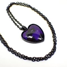 Nice Goth heart design with black chain and setting. The resin cab is pearly black with a bluish pearly purple that can be more purple or more blue in color depending on how the light hits it. Size: Chain is 24" long. Pendant is 1 3/8" x 1" in size including the bail. Type: New, Handmade by Sharky.  Condition: Made with all new materials. Please note that handmade resin pieces may include small imperfections and slight differences in pattern and color. Materials: Black coated base metal, resin. Purple Resin, Bluish Purple, Goth Jewelry, Purple Jewelry, Purple Necklace, Womens Jewelry, Black Chain, Long Pendant, Heart Pendant Necklace