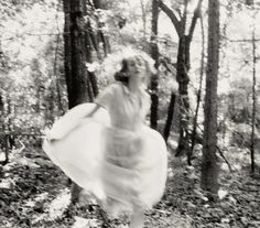 a woman in a dress is running through the woods