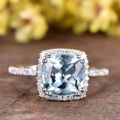 a cushion cut blue topaz surrounded by pave diamond halos on a wooden surface