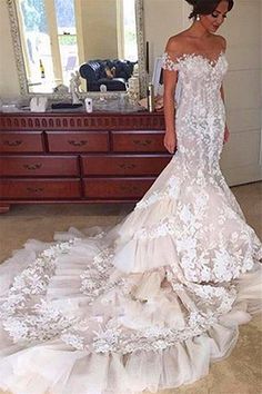 a woman in a wedding dress standing next to a dresser