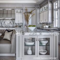 a large kitchen with marble counter tops and white cabinets, along with a gray couch