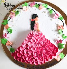 a birthday cake decorated with pink flowers and a woman in a dress on it's side