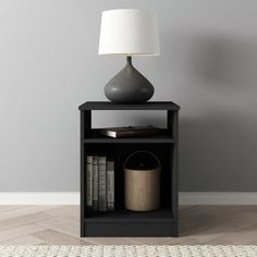 a black book shelf with a lamp on top and books in the bottom corner next to it