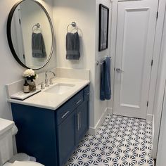 a bathroom with blue and white tile on the floor, toilet, sink and mirror