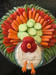 a platter with carrots, celery, cucumbers and dip