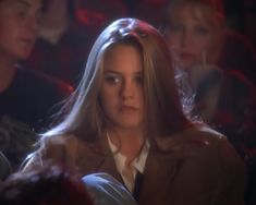 a woman with long hair sitting in front of other people