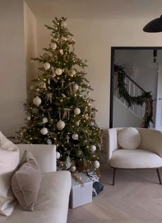 a living room with a christmas tree in the corner and two chairs next to it