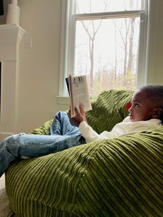 a young boy sitting in a bean bag chair reading a book