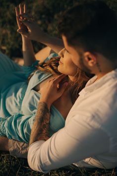 a man and woman laying on the ground together with their hands up to each other