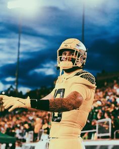 a football player in uniform standing on the sidelines with his arms out and hands outstretched