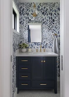 a bathroom with blue and white wallpaper on the walls, two sinks and a mirror