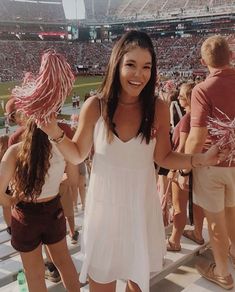 a woman standing in front of a crowd at a baseball game with her hair pulled back