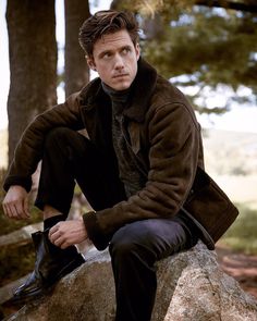 a man sitting on top of a large rock