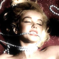 a woman laying on top of a bed covered in pearls and chains with her eyes closed