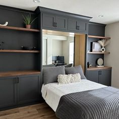 a bed sitting under a mirror in a bedroom next to a wall mounted bookshelf