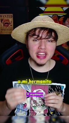 a young man wearing a straw hat and holding up a comic book with his mouth open