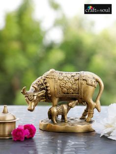 an elephant figurine sitting on top of a table next to a pink flower