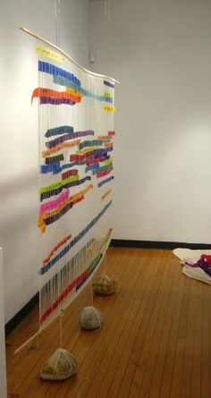 a wall hanging made out of yarn with shoes on the floor in front of it