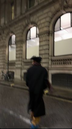 a blurry photo of a man walking down the street in front of a building