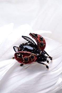 two lady bug brooches sitting on top of a white cloth covered tablecloth