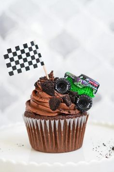 a cupcake topped with chocolate frosting and a green monster truck flag on top