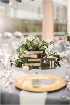 the table is set with books, flowers and wine glasses for an elegant wedding reception