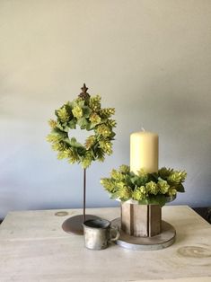 a table with a candle and some wreaths on it next to a small cup