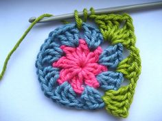 a crochet flower is being worked on by a knitting needle and yarn ball