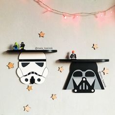 two star wars themed items are hanging on the wall next to a string of lights