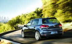 the back end of a silver volkswagen car driving down a road