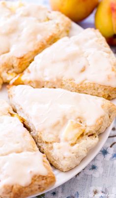 glazed scones on a white plate next to some peaches and an apricot