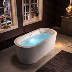 a bath tub with blue water in the middle of a room next to two windows