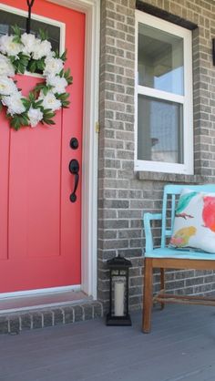 a blue chair sitting in front of a red door with a wreath on it's side