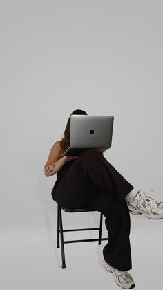 a woman sitting in a chair with her laptop on her lap and head resting on her hand