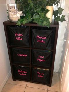 a wooden shelf with four black bags on top of it next to a potted plant