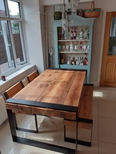 a wooden table sitting in the middle of a kitchen next to an open cabinet and window