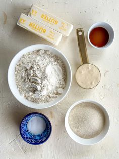 three bowls with different ingredients in them on a white counter top next to two spoons