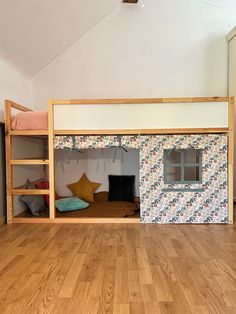 a bunk bed in the middle of a room with wooden floors and walls, next to a window