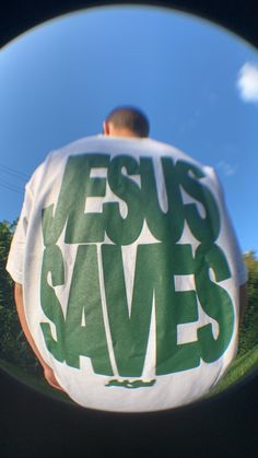 the reflection of a man holding a jesus saves t - shirt in front of his face