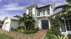 a white house with black shutters and palm trees