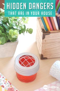 a jar filled with colored pencils sitting on top of a table next to a potted plant