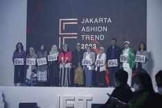 a group of people standing on top of a stage holding up pictures with words above them