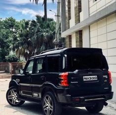 a black suv parked in front of a tall building with palm trees on both sides