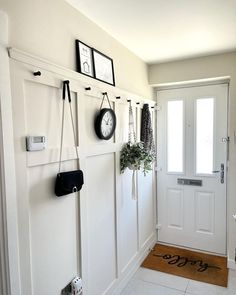 there is a clock hanging on the wall next to a door and some plants in pots