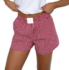 a woman in red and white striped shorts with her hands on her hips, wearing a white t - shirt