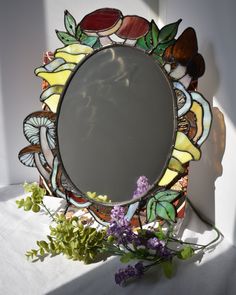 a mirror sitting on top of a table next to flowers