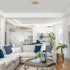 a living room with white couches and blue pillows on the back of the couch